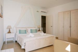a white bedroom with a white bed with blue pillows at Lindos Harmony Suites in Lindos +60 photos
