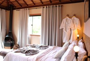 a bedroom with a bed with clothes hanging on a wall at Chalé Refugio Vale da Mantiqueira, Visconde de Mauá in Visconde De Maua