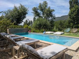 a swimming pool with chaises and chairs next to at Bulles d'Olive Provence avec piscine - Jacuzzi en option in Nyons