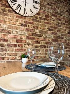 a table with two glasses and a clock on a brick wall at Appartement Spacieux T1bis - Centre-ville in Agen