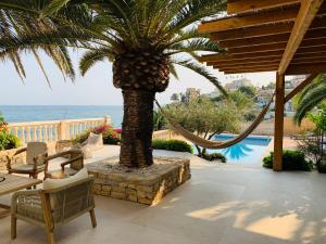 a patio with a palm tree and hammocks and the ocean at Villa Mar in El Campello