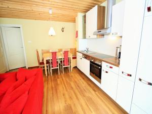 cocina con sofá rojo y mesa en Apartment in St Michael near Ski Slopes, en Sankt Michael im Lungau