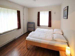 a bedroom with a bed with white sheets and two windows at Apartment in St Michael near Ski Slopes in Sankt Michael im Lungau
