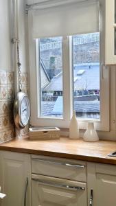a kitchen counter with a clock and two windows at VIKARO Apartment in Monschau