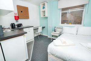 a small room with a bed and a kitchen at Lovely Modern Central Coventry Budget Studio in Coventry