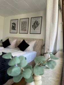 a bedroom with two beds and a plant in the foreground at RheinLoft Apartment - Balkon & Parkplatz "optional" am Deutschen Eck in Koblenz