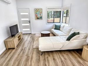 a living room with a couch and a tv at Kahibah Guesthouse in Kahibah