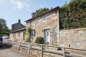 a stone building with a white door on a street at Host & Stay - Brackenrigg Cottage in Rothbury