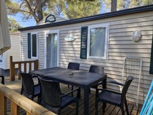 a black table and chairs on a deck with a house at Camping Onlycamp Les Chênes Verts in Cabrières-dʼAigues