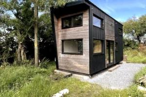a black tiny house on a gravel lot at Tiny Home - Huge Views - Coastal - Surf in Sligo