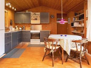een keuken met een tafel met stoelen en een roze lamp bij 6 person holiday home in Rødby in Rødby
