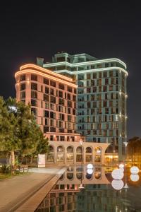 a large building at night with its reflection in the water at Archotel Avenue in Odesa