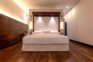 a large white bed in a room with wooden floors at The Fortress Resort & Spa in Ahangama