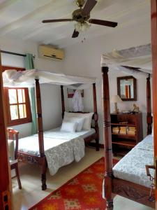 Un dormitorio con dos camas y un ventilador de techo. en Kobe House, en Malindi