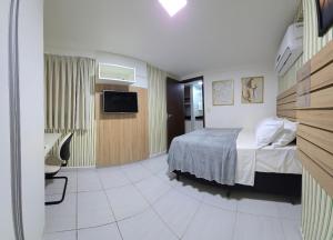 a hotel room with a bed and a television at Moriah by Hosppedar in Tambaú
