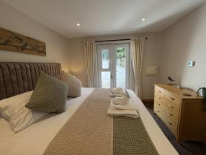 a bedroom with a bed with a dresser and a window at Mi Casa Su Casa - Mount Brioni in Downderry