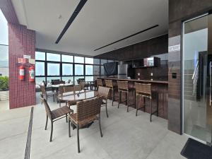 a restaurant with tables and chairs and a kitchen at One Way by Hosppedar in Tambaú