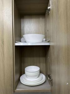 a cabinet with plates and bowls on a shelf at Fame Residences in Sampong +1 photo