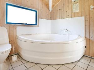 a white bath tub in a bathroom with a window at Cozy Retreat with Spa - By Traum Ferienwohnungen in Stenbjerg