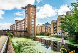 a building with a tower next to a river with green algae at York Cocoa Suites - city centre apartments in York