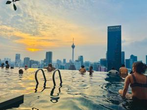 a group of people in a infinity pool with a city skyline at Axon Residence KL Pavilion in Kuala Lumpur