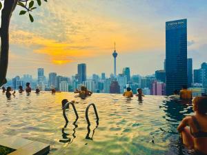 a group of people in a infinity pool with a city skyline at Axon Residence KL Pavilion in Kuala Lumpur