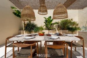 a dining room table with rattan chairs and a table and chairsktop at Casa Piccadilly - Óbidos Design Villa, Surf & Golf in Sobral