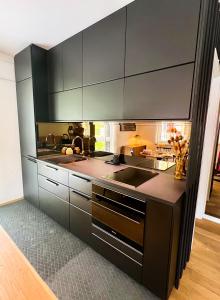 a kitchen with black cabinets and a sink at Lux city apartment in Luxembourg