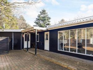 a black house with a porch and glass doors at Seaside Charm in albaek - By Traum Ferienwohnungen in Spottrup