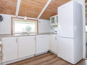 a kitchen with white cabinets and a white refrigerator at 4 star holiday home in Rømø in Bolilmark