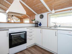 a kitchen with white cabinets and a sink and a stove at 4 star holiday home in Rømø in Bolilmark +27 photos
