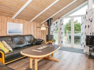 a living room with a leather couch and a table at 6 person holiday home in Rømø in Bolilmark