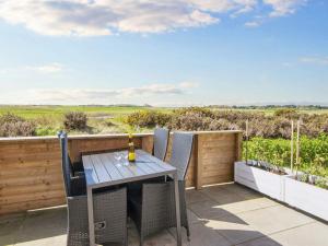 a table and chairs on a patio with a view at Golf View Retreat - By Traum Ferienwohnungen in Rømø Kirkeby