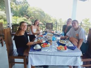a group of people sitting around a table with food at Ella Tea House Garden in Badulla