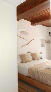 a bedroom with a bed with white walls and wooden ceilings at Paros Heritage Retreat by ΜΡS in Parikia