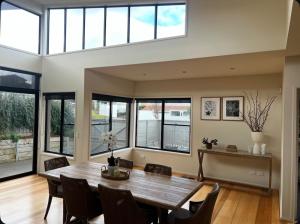 a dining room with a table and chairs and windows at Highton Hideaway in Highton