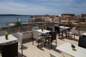 a patio with tables and chairs on a roof at Livingston Hotel in Siracusa