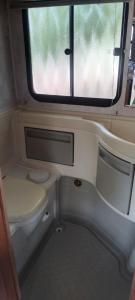 a small bathroom with a toilet and a window at Le camping-car de la Gardié in Vielmur-sur-Agout