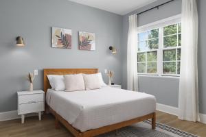 a white bedroom with a bed and a window at Hip New Condo near Broadway and Trendy East Nash with 5 Beds in Nashville