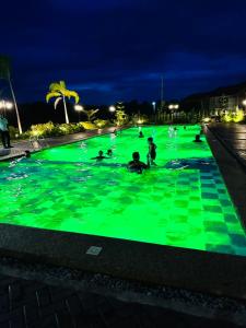 eine Gruppe von Menschen, die in einem Pool mit grüner Beleuchtung schwimmen in der Unterkunft Elegant 3 Bedroom House near Airport in Sampong