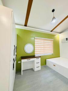 ein Schlafzimmer mit einem Schreibtisch und einer grünen Wand in der Unterkunft Elegant 3 Bedroom House near Airport in Sampong