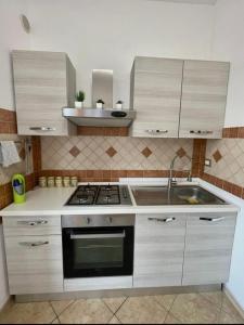 a kitchen with white cabinets and a stove and a sink at Casa Talìa in Centuripe +7 photos
