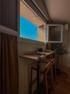 Una pequeña cocina con una mesa y una ventana. en Charmant 2 pièces rénové avec vue mer, en Villefranche-sur-Mer