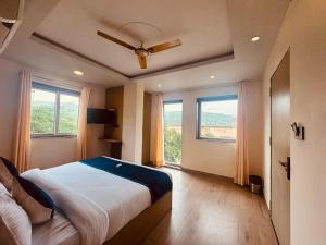 a bedroom with a bed with a ceiling fan and windows at The kanak valley Hotel in Jaipur +8 photos