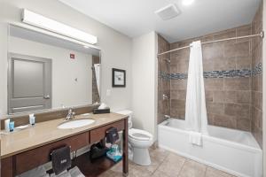 a bathroom with a sink and a toilet and a mirror at Independence Stay Long Term and Suites in Marinette