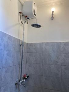 a shower in a bathroom with a light on the wall at Mlimani city studio apartment in Dar es Salaam
