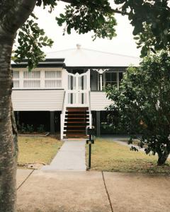a large white house with a porch and stairs at Urban Getaway Colonial 6 beds 2 bath aircon pet family in Bundamba