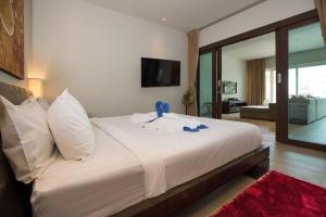 a bedroom with a large white bed with a tv on the wall at Tropical Serenity - Elegant 1 Bedroom with Pool in Ban Saiyuan (1)