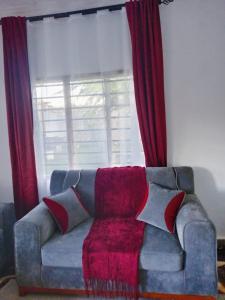 Ukunda AirportにあるDevkim staysの赤いカーテン付きの窓の前に座るソファ