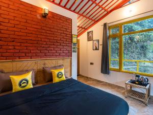 a bedroom with a brick wall and a bed with yellow pillows at The Hosteller Mussoorie By the Streamside, Kempty in Mussoorie
